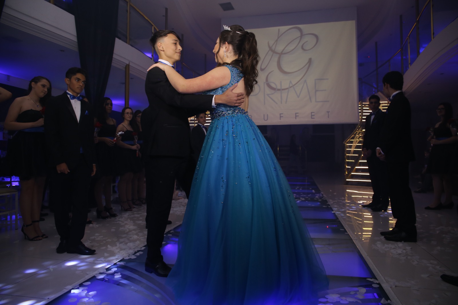Debutante de vestido azul dançando a valsa com iluminação azul na pista