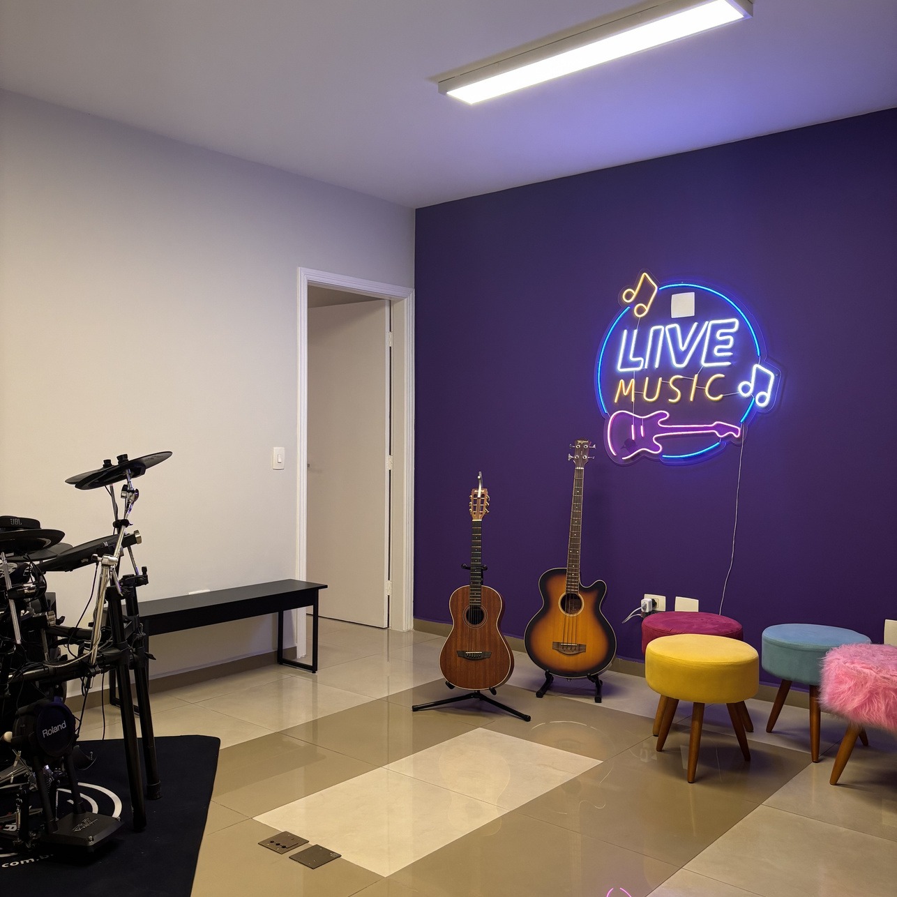 Sala de Música do Dancefloor com parede roxa, neon 'Live Music', violões e bateria